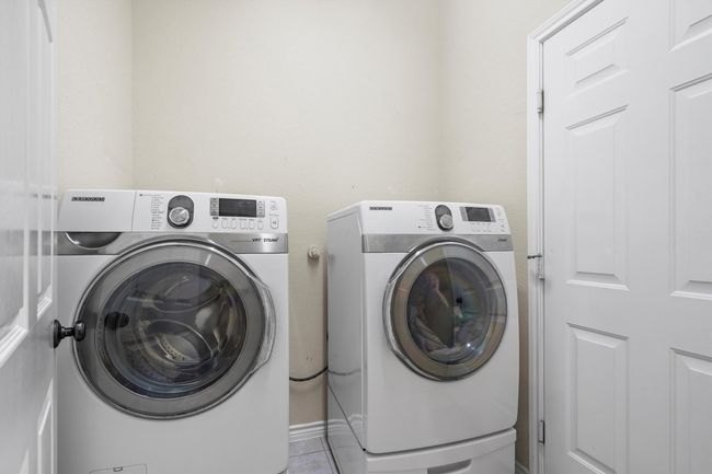 Washroom featuring washing machine and dryer and light tile patterned floors | Image 34