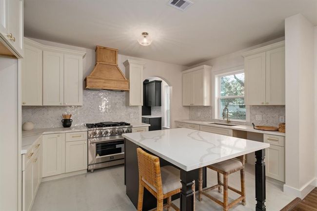 The large island not only provides casual dining space but also offers ample storage, while gorgeous quartz countertops and a glass tile backsplash elevate the kitchen’s aesthetic. | Image 14