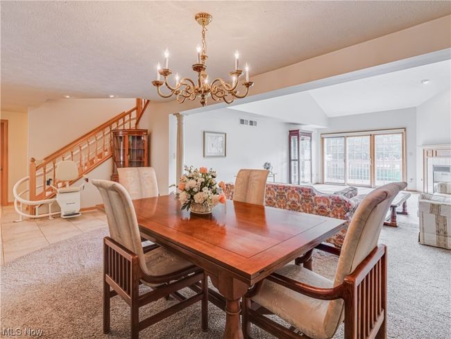 Carpeted dining space with a textured ceiling, a chandelier, and lofted ceiling | Image 14