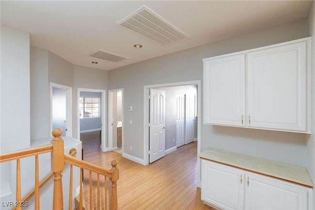 Hallway with an upstairs landing, visible vents, baseboards, and light wood-style flooring | Image 32