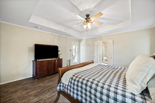 Bedroom featuring a raised ceiling, crown molding, wood finished floors, and visible vents | Image 17