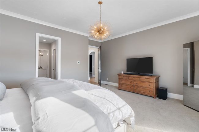 Primary suite with ornamental molding, connected bathroom, and a notable chandelier | Image 16
