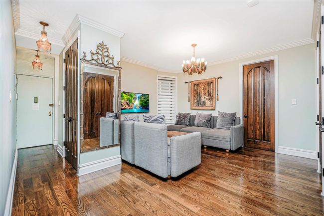 Living area with a chandelier, dark wood-style floors, and crown molding | Image 5