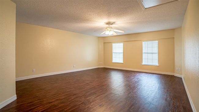 Empty room with dark wood-style flooring, ceiling fan, a textured ceiling, and baseboards | Image 19