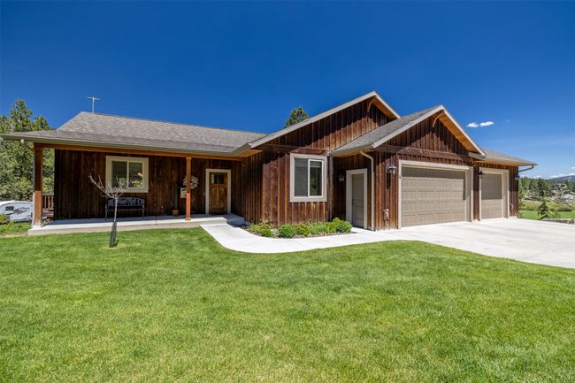 View of front facade featuring an attached garage, board and batten siding, a front yard, and concrete driveway | Image 48