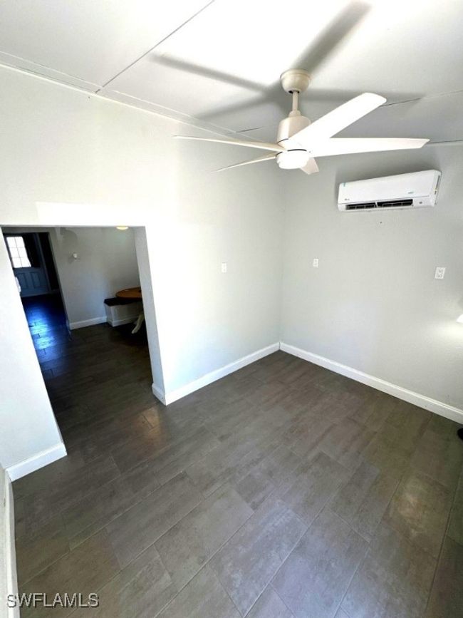 Unfurnished room with baseboards, dark wood-type flooring, an AC wall unit, and a ceiling fan | Image 6