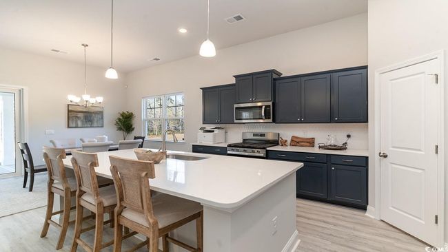 Kitchen with light wood-type flooring, appliances with stainless steel finishes, a kitchen island with sink, and sink | Image 16