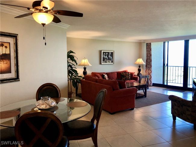 Dining space with ceiling fan, a wall of windows, light tile patterned floors, and ornamental molding | Image 7