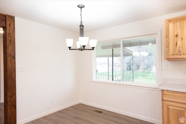 Unfurnished dining area featuring baseboards, wood finished floors, and a notable chandelier | Image 14