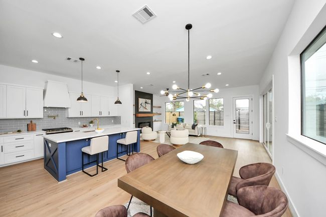 This dining room is bathed in naturallight streaming through expansivewindows and features a modern chandelier. | Image 11