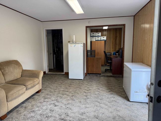 Carpeted living area with a desk and wooden walls | Image 20