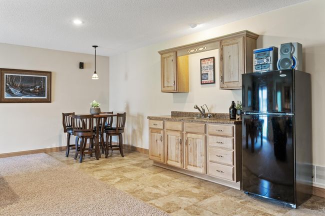Enjoy a pub/game table area with pendant lighting, an ideal custom wet bar & recessed accent light, ceramic tile flooring in just the right area that transitions into neutral carpet. | Image 27