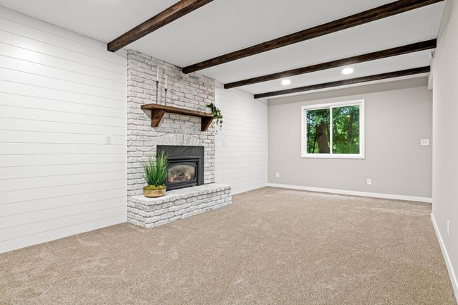 Heading down to the lower level, you have a large family room with limewashed brick gas fireplace and wood mantle. Highlighted with shiplap walls and wood beam ceilings. All new carpet and trim. | Image 13