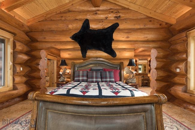 Main level primary bedroom with lofted beamed ceiling and log walls. | Image 15