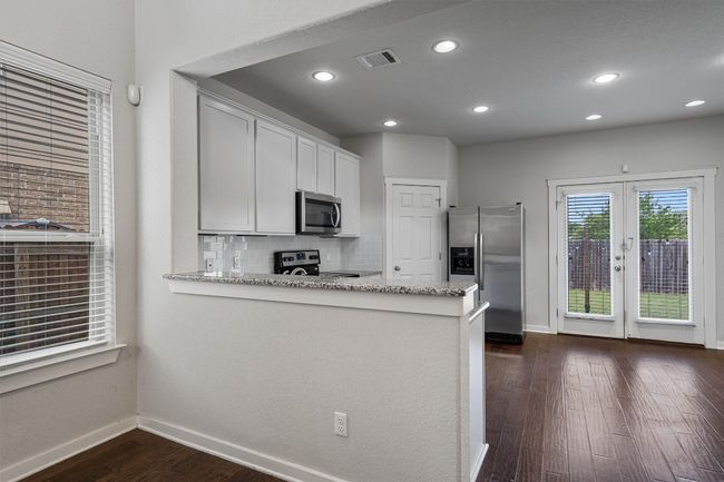 Kitchen featuring appliances with stainless steel finishes, dark wood-style floors, tasteful backsplash, light stone countertops, and recessed lighting | Image 14