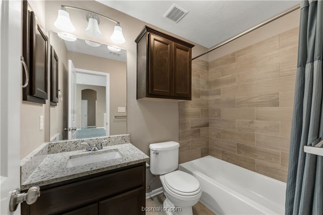 Full bathroom with vanity, shower / bath combination with curtain, and toilet | Image 23