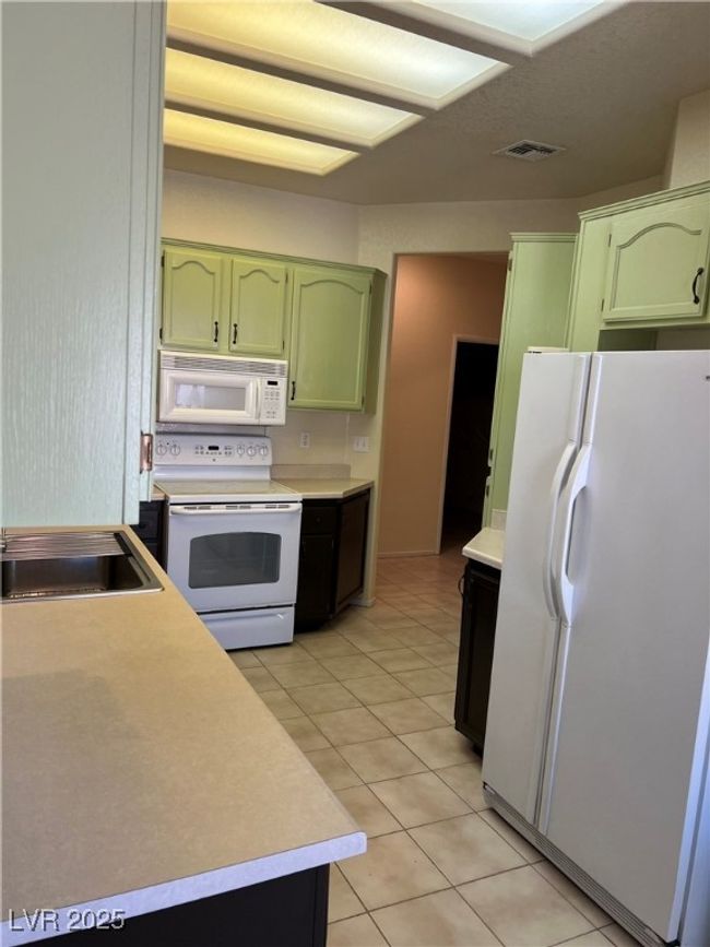 Kitchen featuring green cabinetry, white appliances, light countertops, and light tile patterned flooring | Image 13