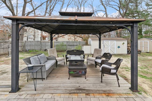 Wooden deck with a gazebo, a shed, a fenced backyard, and an outdoor hangout area | Image 25