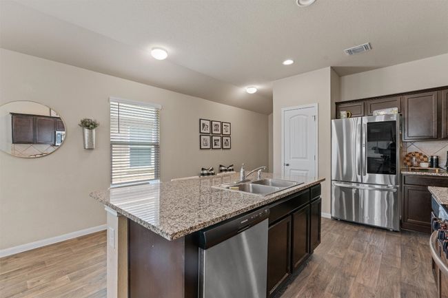 Kitchen with appliances with stainless steel finishes, wood finished floors, dark brown cabinetry, an island with sink, and recessed lighting | Image 8