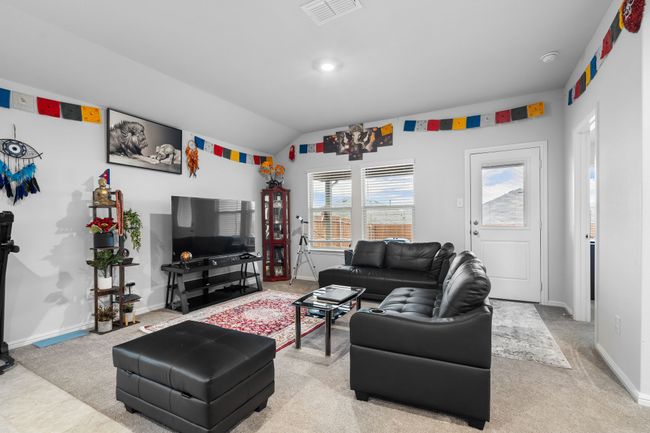 Living area featuring baseboards, visible vents, vaulted ceiling, and light carpet | Image 12