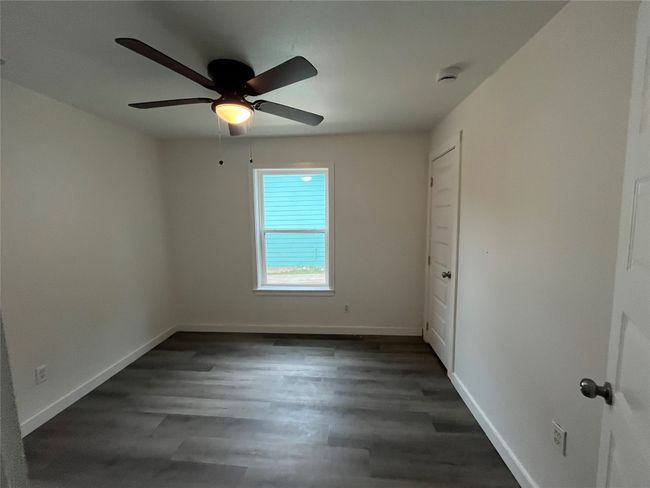 Unfurnished room with ceiling fan, baseboards, dark wood-style floors, and a smoke detector | Image 6