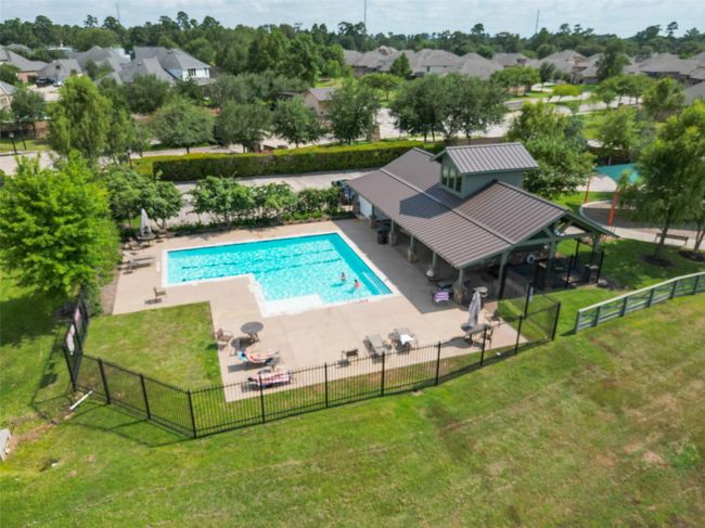 The neighborhood recreational area featuring a fenced-in pool with adjacent lounging space, a covered pavilion, and lush greenery. It's perfect for outdoor relaxation and community gatherings. | Image 34