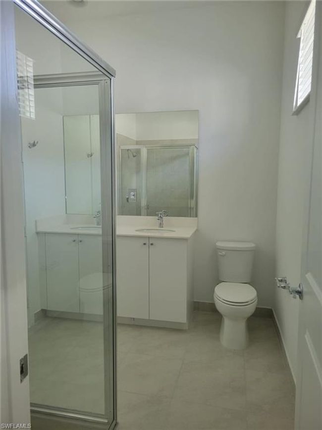 Full bath featuring toilet, a stall shower, vanity, baseboards, and tile patterned flooring | Image 20
