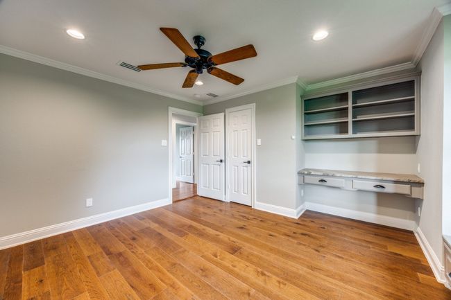 Unfurnished bedroom featuring built in desk, light wood finished floors, recessed lighting, crown molding, and ceiling fan | Image 19