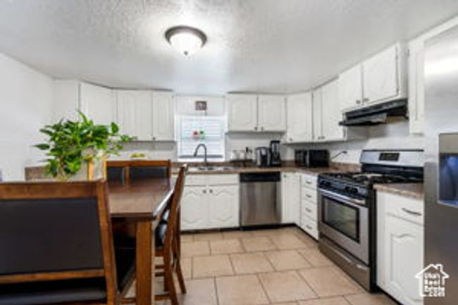Kitchen with a sink, white cabinets, appliances with stainless steel finishes, and under cabinet range hood | Image 11