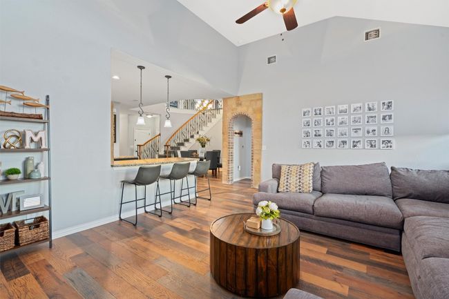 Living area with ceiling fan, stairway, wood finished floors, high vaulted ceiling, and arched walkways | Image 14