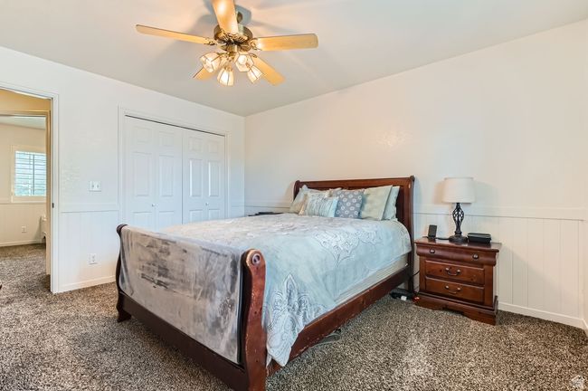 Bedroom with carpet floors, a wainscoted wall, a closet, and ceiling fan | Image 12