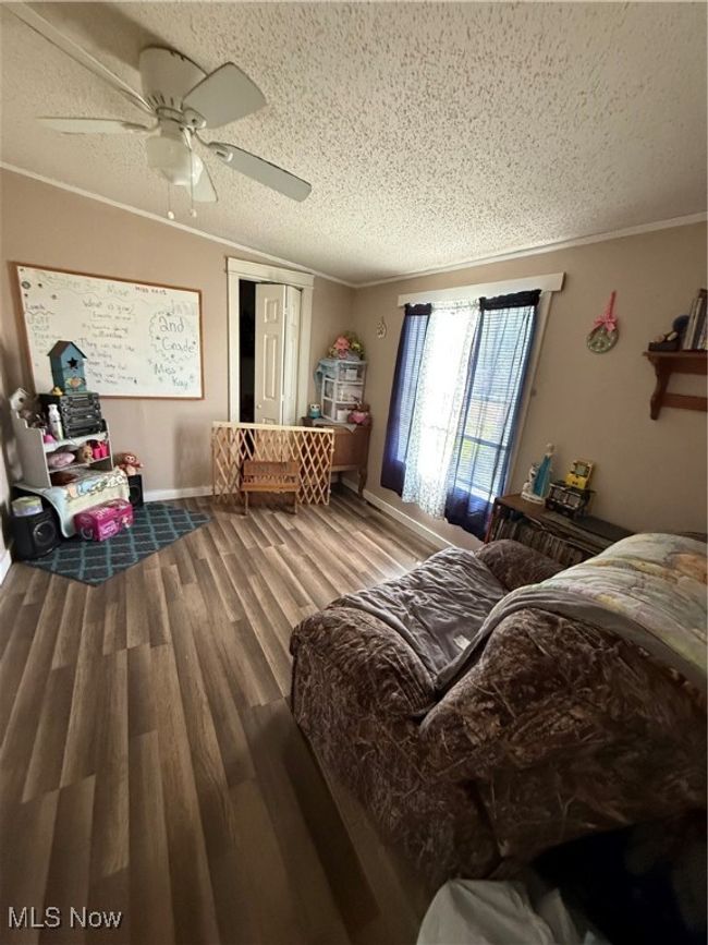 Bedroom featuring wood finished floors, a ceiling fan, crown molding, baseboards, and a textured ceiling | Image 25