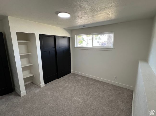Unfurnished bedroom with light colored carpet, a textured ceiling, and a closet | Image 20