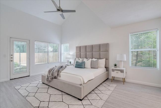 Bedroom featuring access to outside, light wood-type flooring, multiple windows, high vaulted ceiling, and baseboards | Image 17