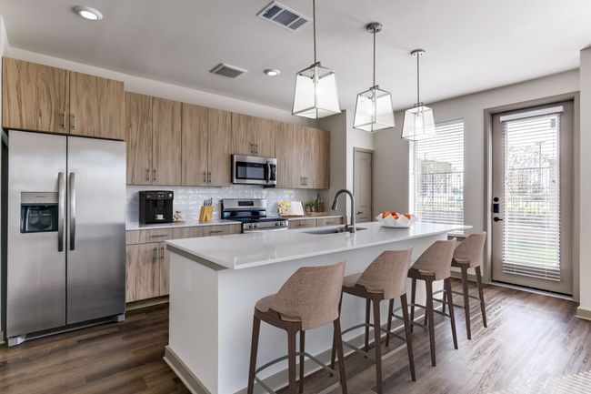 Kitchen with sink, stainless steel appliances, an island with sink, a kitchen bar, and decorative light fixtures | Image 16