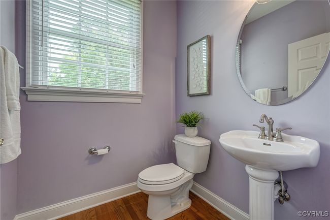 Main-level half bath with hardwood floors, pedestal sink, and a window for natural light—conveniently located next to the office. | Image 17