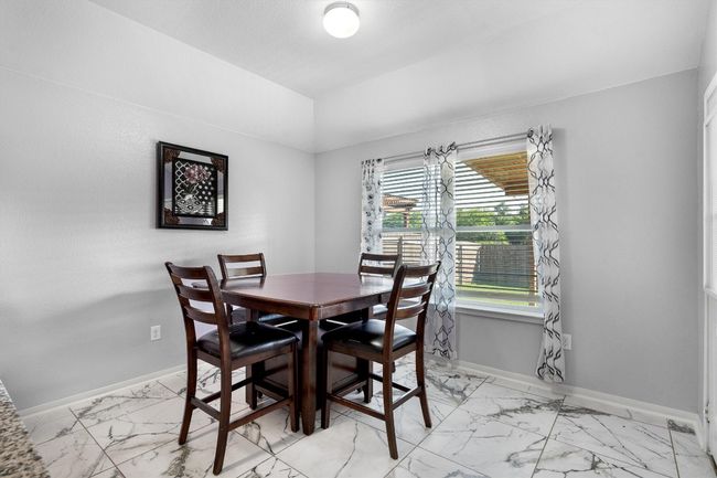 Dining room featuring light marble finish flooring, baseboards, and lofted ceiling | Image 7