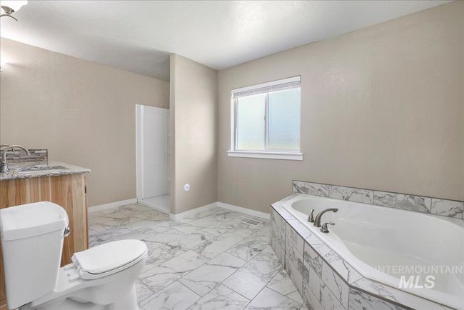 Bathroom featuring a bath and marble look tiles | Image 5