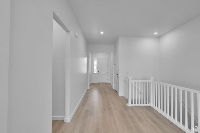Hall with light wood finished floors, recessed lighting, baseboards, and an upstairs landing | Image 7