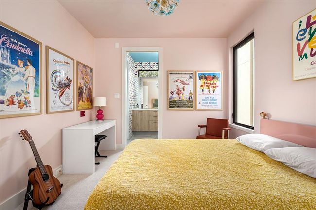 This whimsical secondary bedroom blends vintage charm with cheerful color, featuring blush pink walls.Perfectly tailored for creativity and comfort. | Image 24