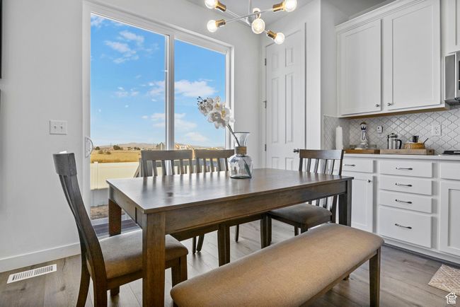 Dining room with visible vents, light wood-style flooring, baseboards, and an inviting chandelier | Image 26