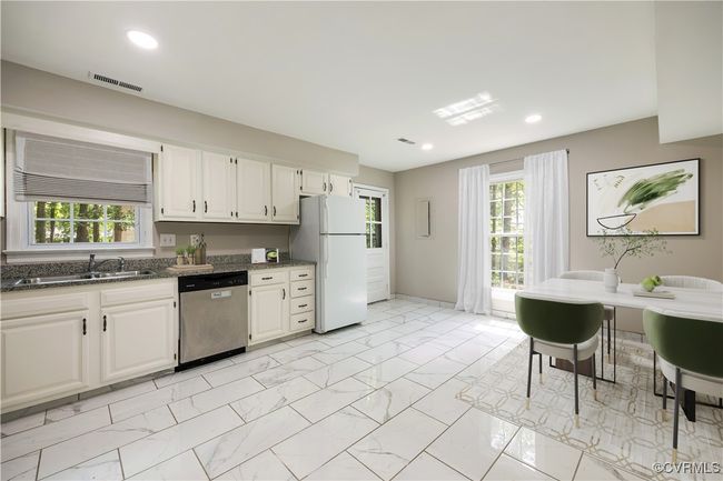 Kitchen with stainless steel dishwasher, freestanding refrigerator, light marble finish floors, dark stone counters, and white cabinetry | Image 11
