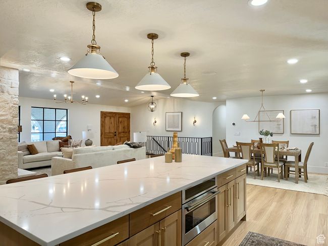 Kitchen featuring a chandelier, recessed lighting, light wood finished floors, open floor plan, and hanging light fixtures | Image 12