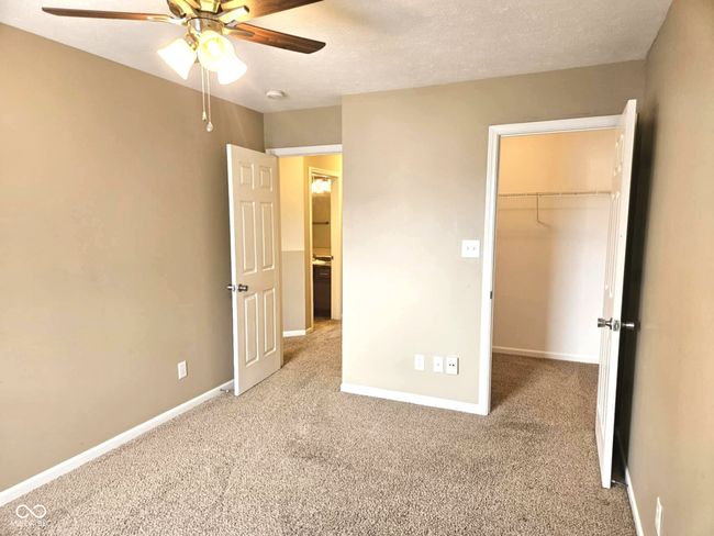 unfurnished bedroom featuring a walk in closet, baseboards, a closet, and carpet | Image 39