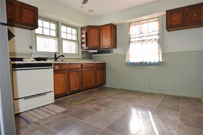 Kitchen featuring a sink, gas range gas stove, brown cabinetry, and wainscoting | Image 11