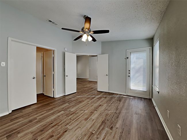 Unfurnished bedroom featuring wood finished floors, a textured ceiling, and ceiling fan | Image 7