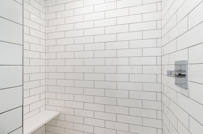 The stunning custom tile walk in shower includes a bench and measures | Image 13