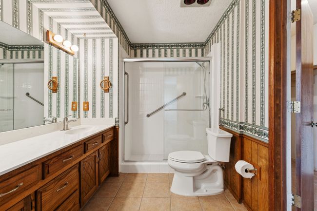 Bathroom featuring wallpapered walls, vanity, a shower stall, a textured ceiling, and tile patterned flooring | Image 20
