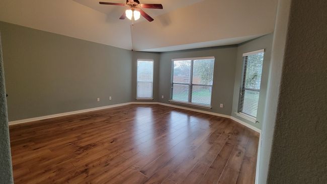 Unfurnished room featuring a ceiling fan, healthy amount of natural light, wood finished floors, baseboards, and vaulted ceiling | Image 14