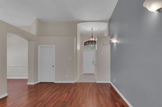 Foyer with arched walkways, wood finished floors, and a chandelier | Image 34